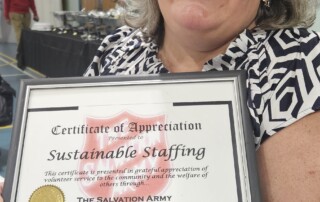Mary McBride holding the The Highest Group Kettle Total Award certificate