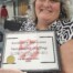 Mary McBride holding the The Highest Group Kettle Total Award certificate